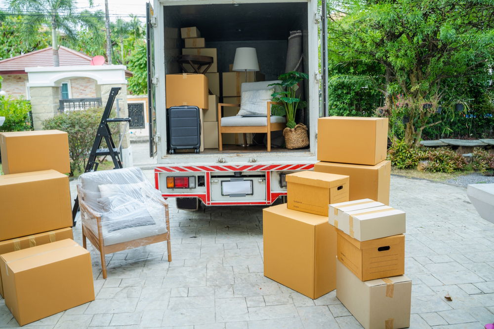 Open moving truck surrounded by boxes and furniture in Saratoga Springs, NY
